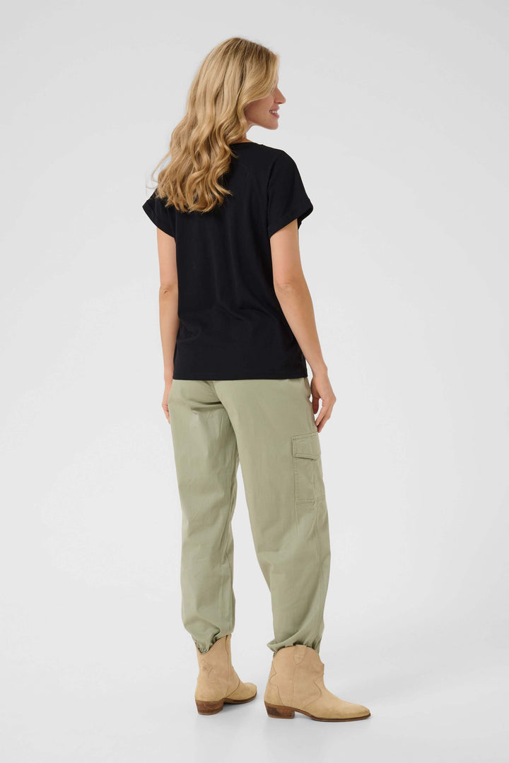 Femme vue de dos portant un t-shirt noir et un pantalon cargo vert, style décontracté et moderne.