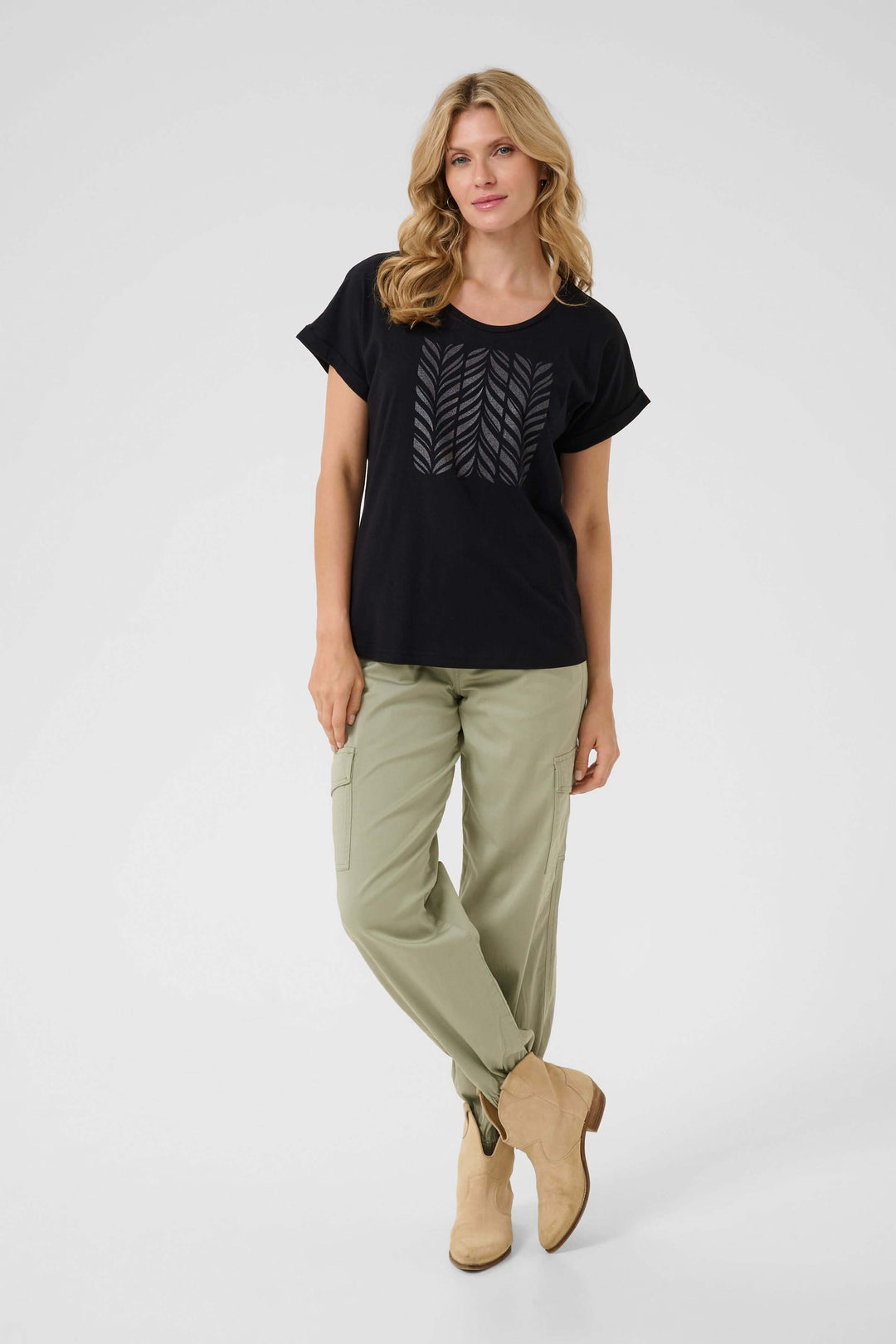 Femme portant un t-shirt noir à imprimé graphique et un pantalon cargo vert, style décontracté.