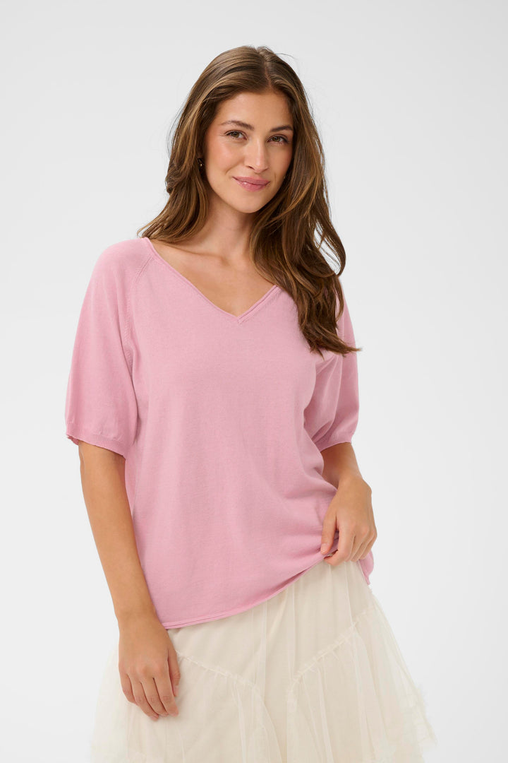 Femme portant un T-shirt Romane rose à encolure en V et manches amples, style décontracté.