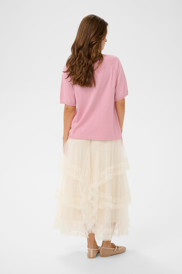 Femme portant le T-shirt Romane rose avec jupe évasée en dentelle, vue de dos, style décontracté et féminin.