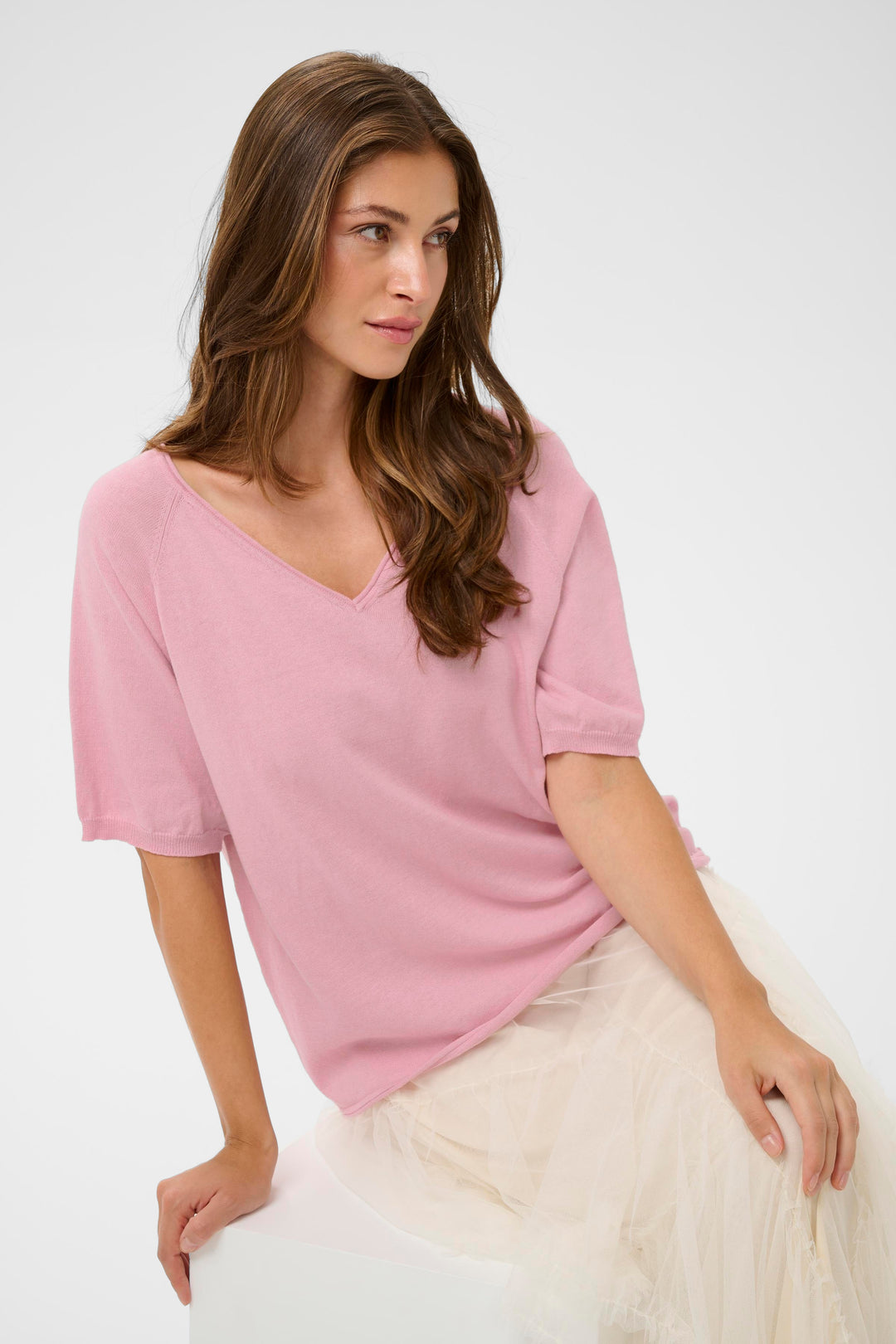 Femme portant un T-shirt Romane rose à manches amples et encolure en V, parfait pour un look décontracté et confortable.