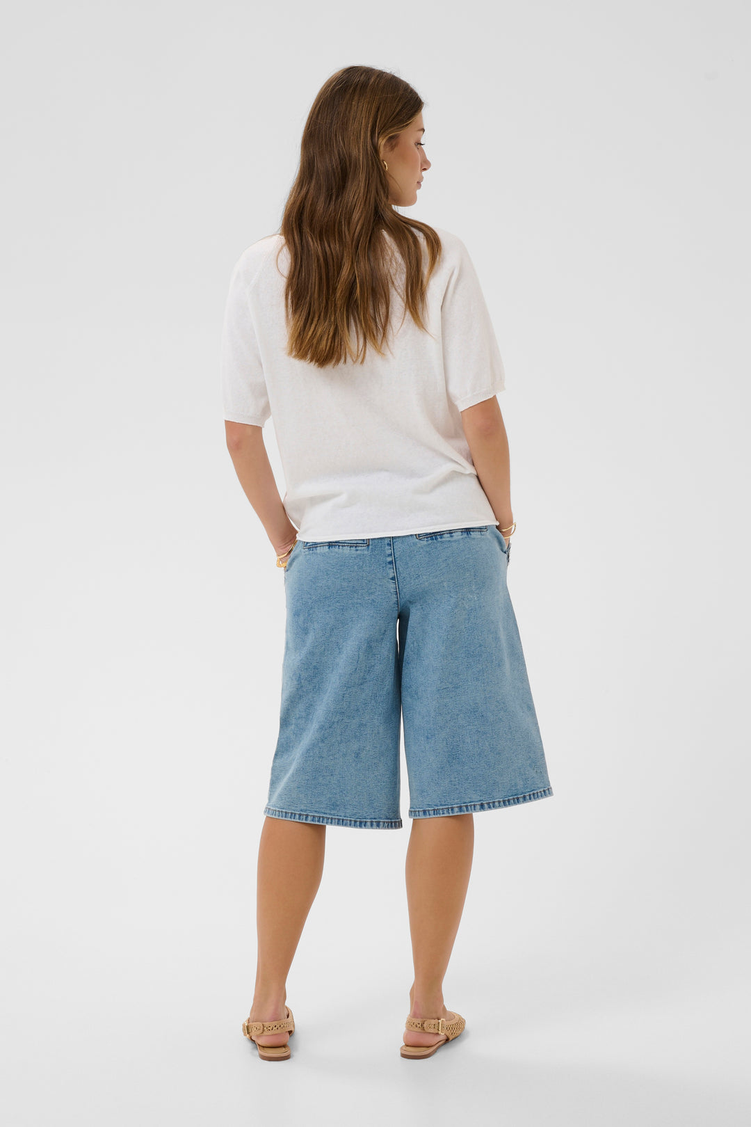 Femme portant un T-shirt Romane blanc à coupe décontractée et bermuda en jean, vue de dos.