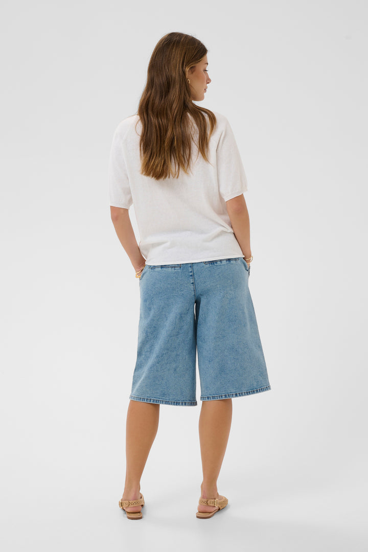 Femme portant un T-shirt Romane blanc à coupe décontractée et bermuda en jean, vue de dos.