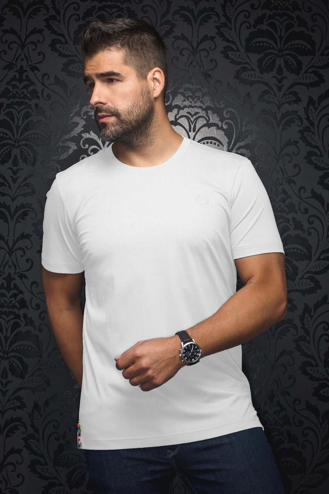 T-shirt Varenna blanc, coupe ajustée, écusson discret, porté avec style sur fond élégant.