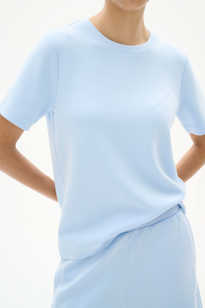 Minimalist light blue T-shirt with short sleeves, soft modal TENCEL™ fabric, showcasing modern comfort.