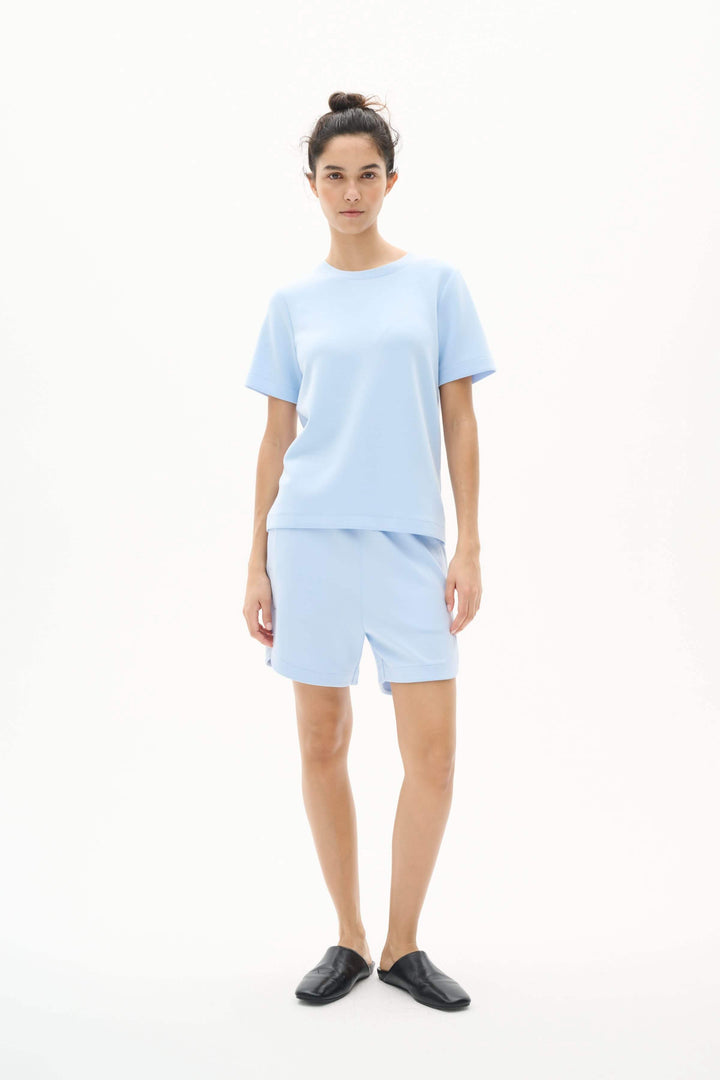 Model wearing light blue T-shirt and shorts set, showcasing modern comfort and relaxed chic style.