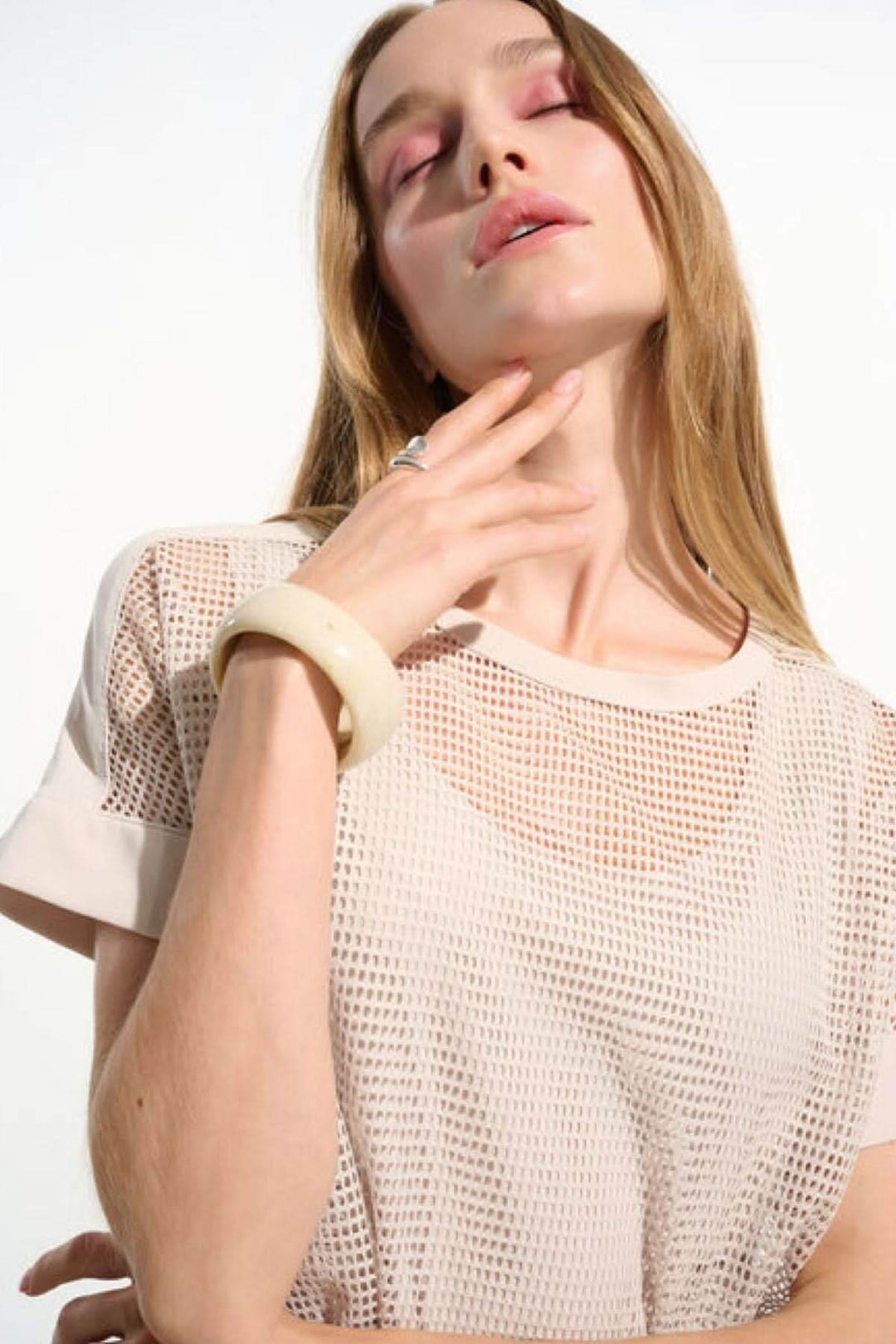 Femme portant un T-shirt ajouré fluide avec manches courtes et maille respirante, ajoutant une touche moderne à sa tenue.