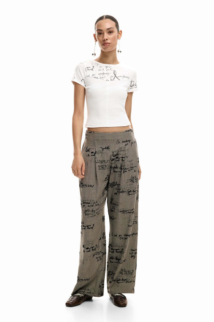 Femme portant un T-shirt ajusté avec lettrage, silhouette moderne et féminine, idéal pour un look épuré avec pantalon imprimé.