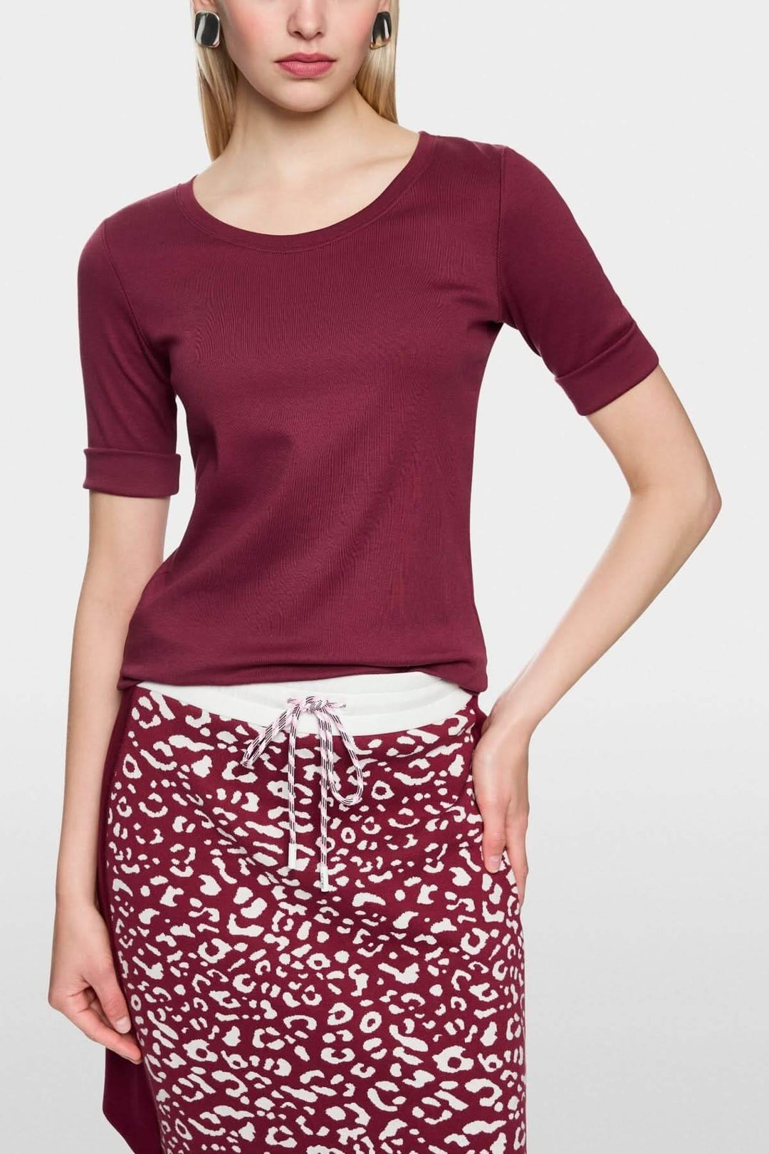 Femme portant un T-shirt ajusté en coton stretch, manches mi-longues retroussées pour un style casual chic.