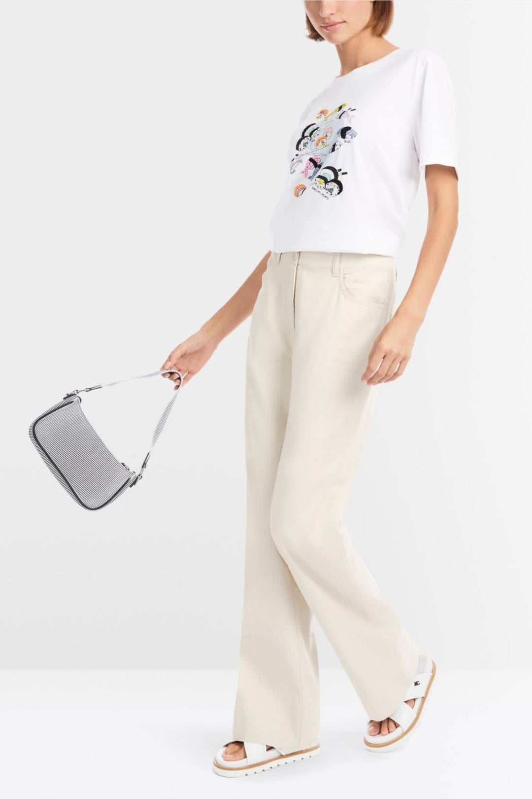 T-shirt blanc avec application sushi colorée, porté avec pantalon beige et sac gris.