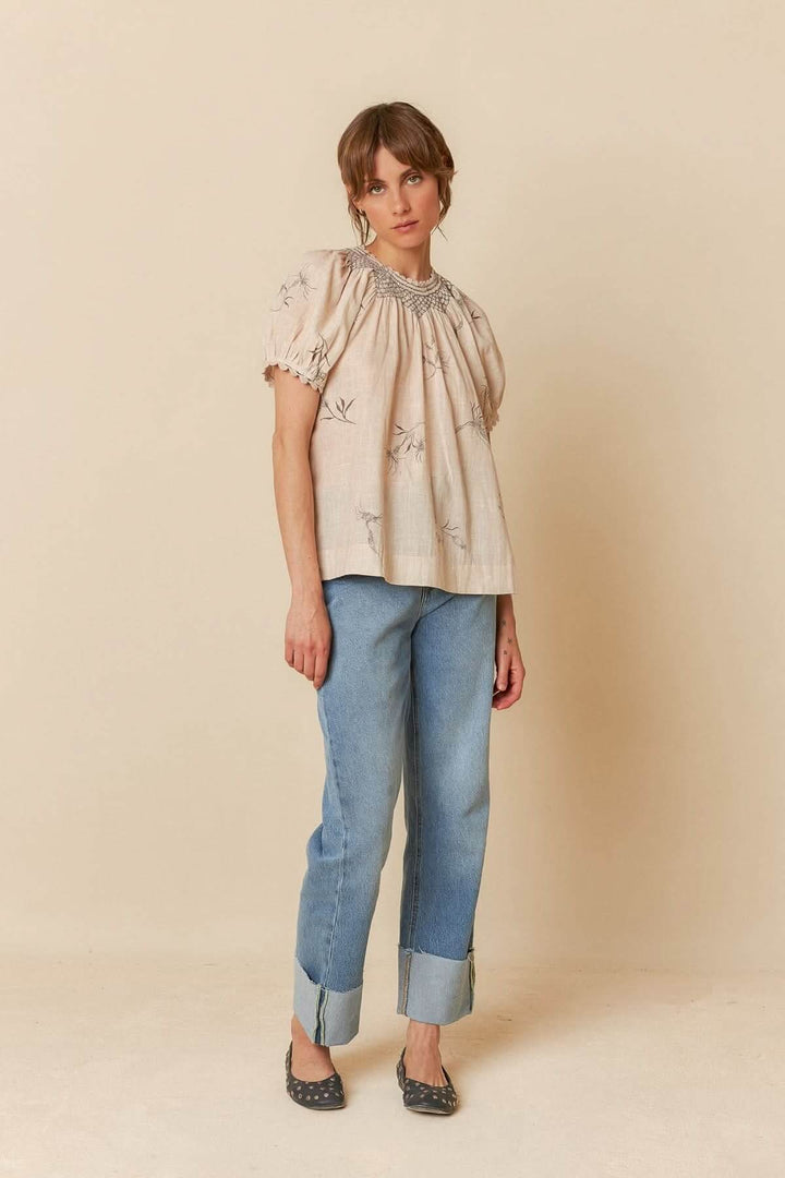 T-shirt à manches bouffantes avec col smocké et imprimé floral, porté avec un jean décontracté.