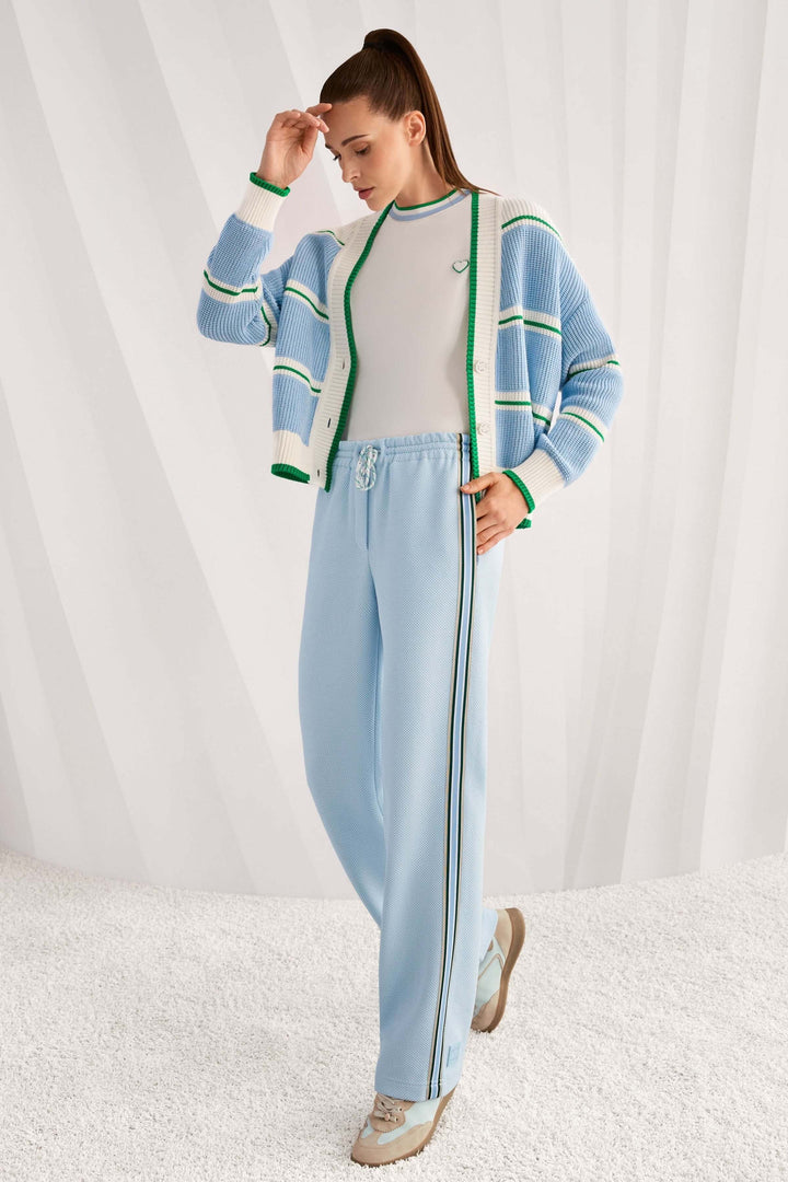 Femme portant un ensemble décontracté avec T-shirt à col contrastant et pantalon bleu clair, style moderne et minimaliste.