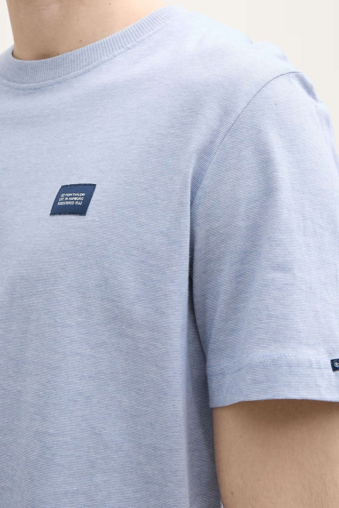 T-shirt bleu clair à manches courtes avec écusson brodé, style minimaliste et confortable.