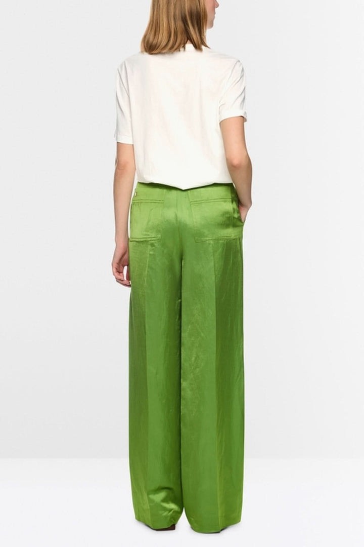 Femme portant un pantalon vert ample et un haut blanc de dos
