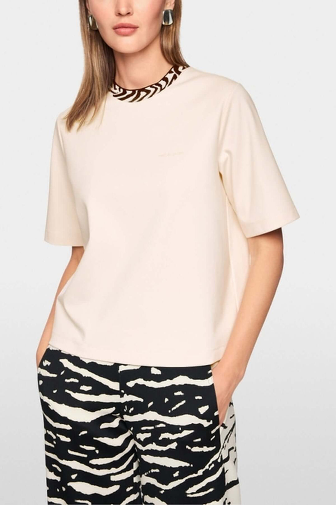 Femme portant un T-shirt classique avec col contrasté et logo Marc Cain Sport, manches courtes et coupe droite.