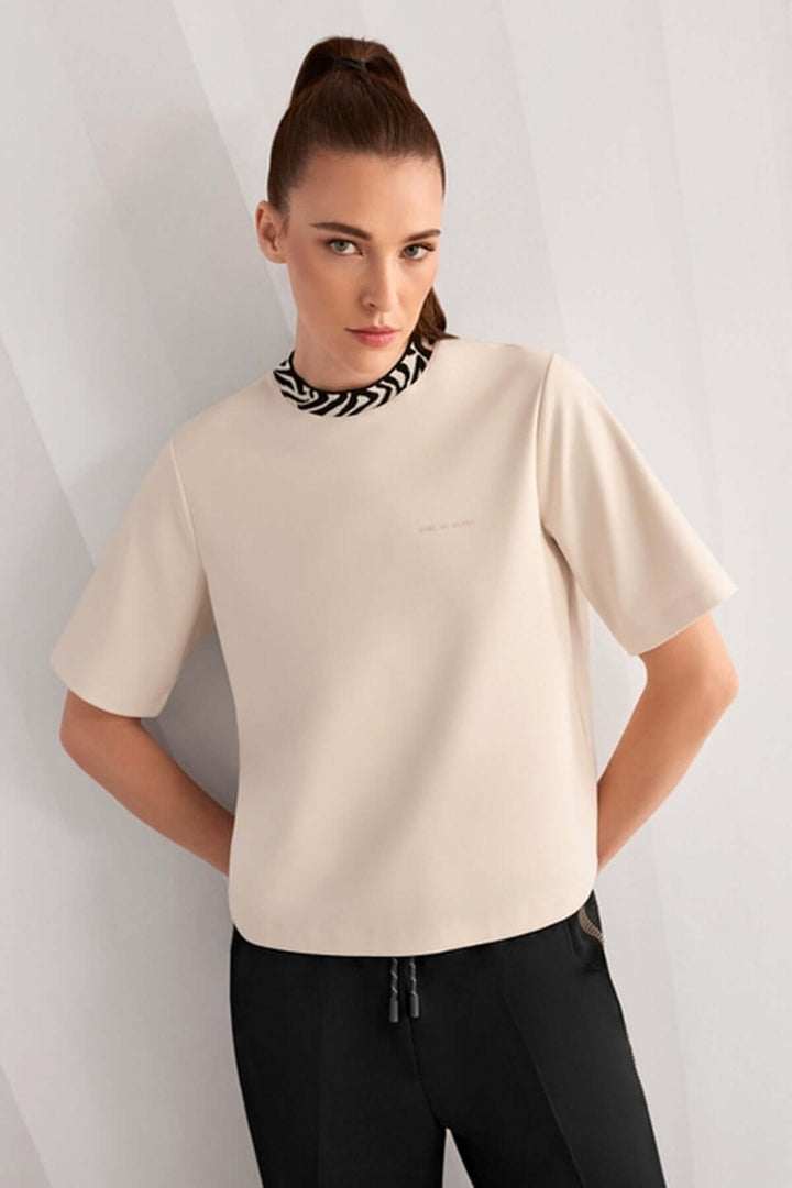 Femme portant un T-shirt classique avec col contrasté et logo Marc Cain Sport, manches courtes, toucher doux, coupe droite.