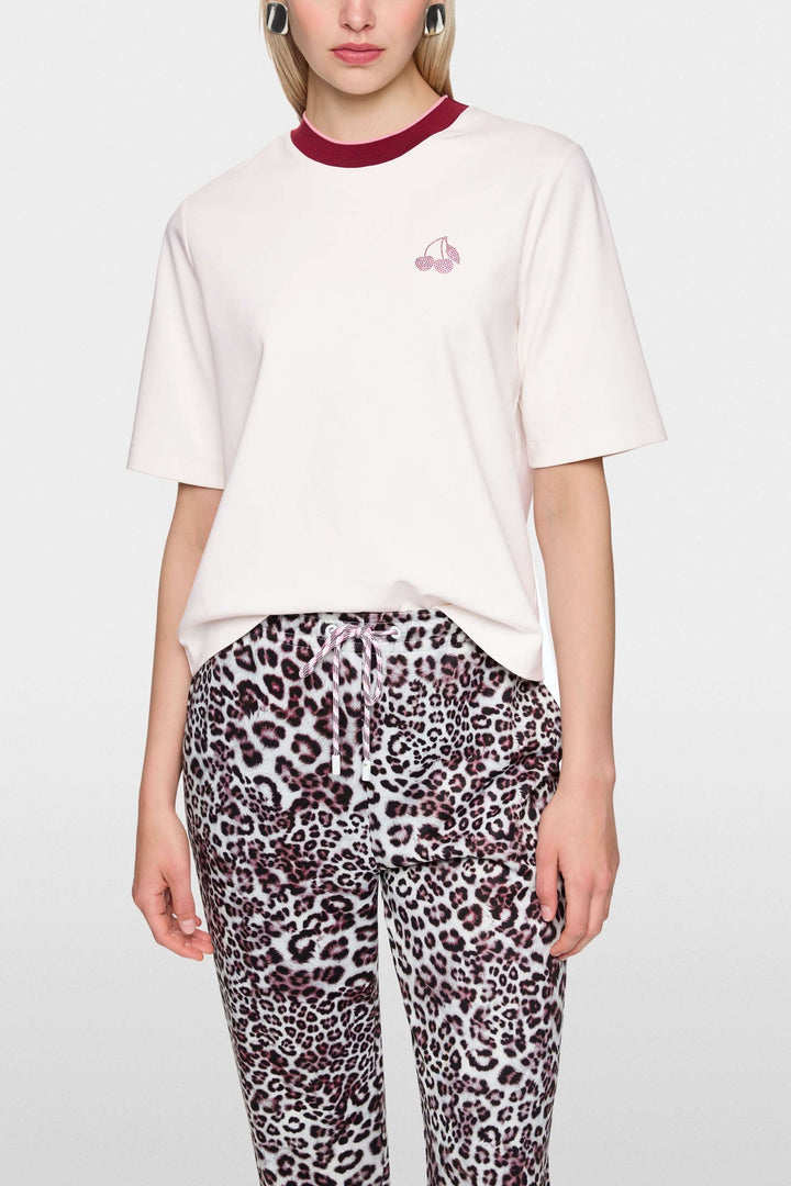 Femme portant un T-shirt classique avec col contrasté et logo Marc Cain Sport, manches courtes, coupe droite, touché doux en coton.