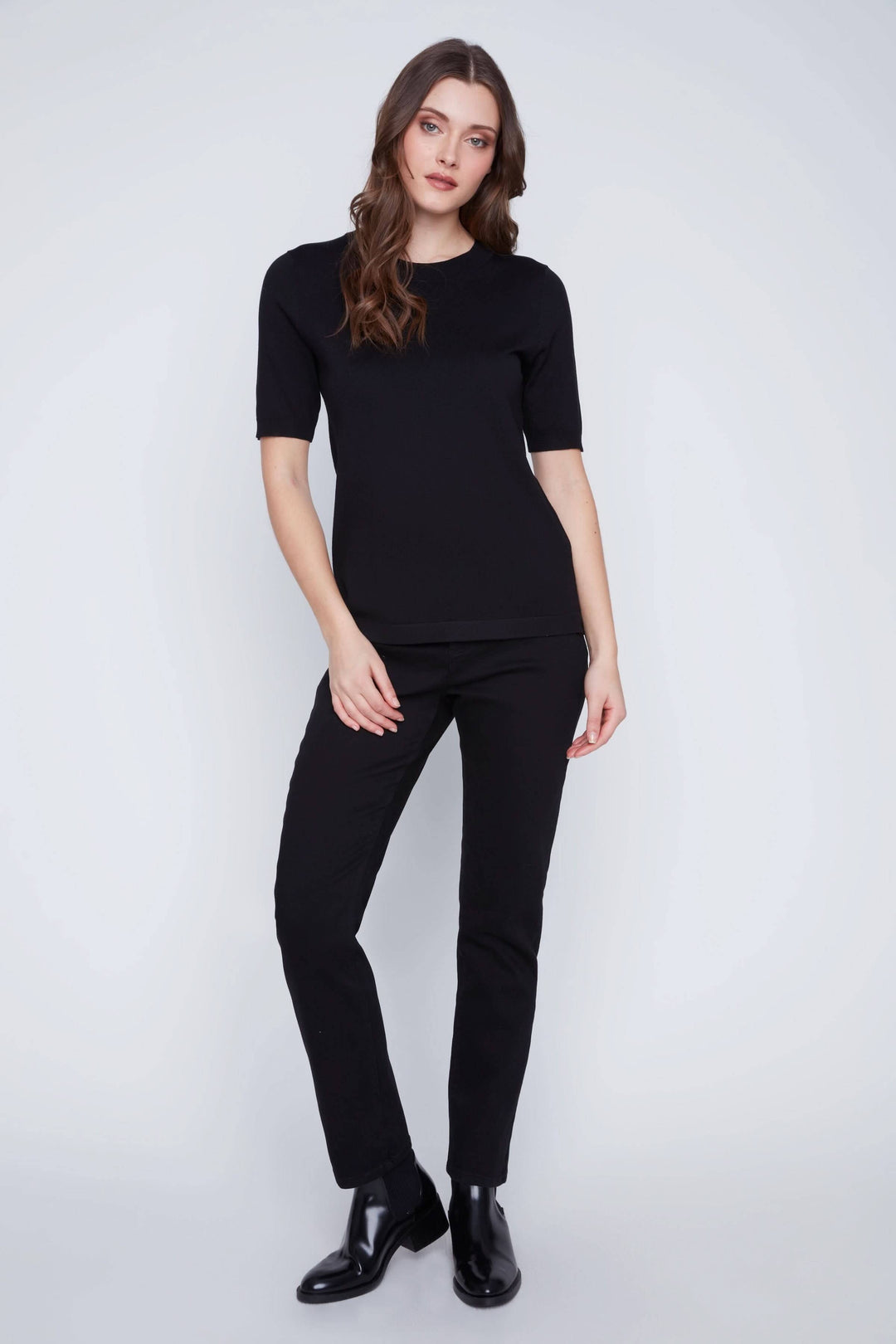 Femme portant un t-shirt classique noir à manches courtes avec un pantalon noir, style minimaliste élégant.