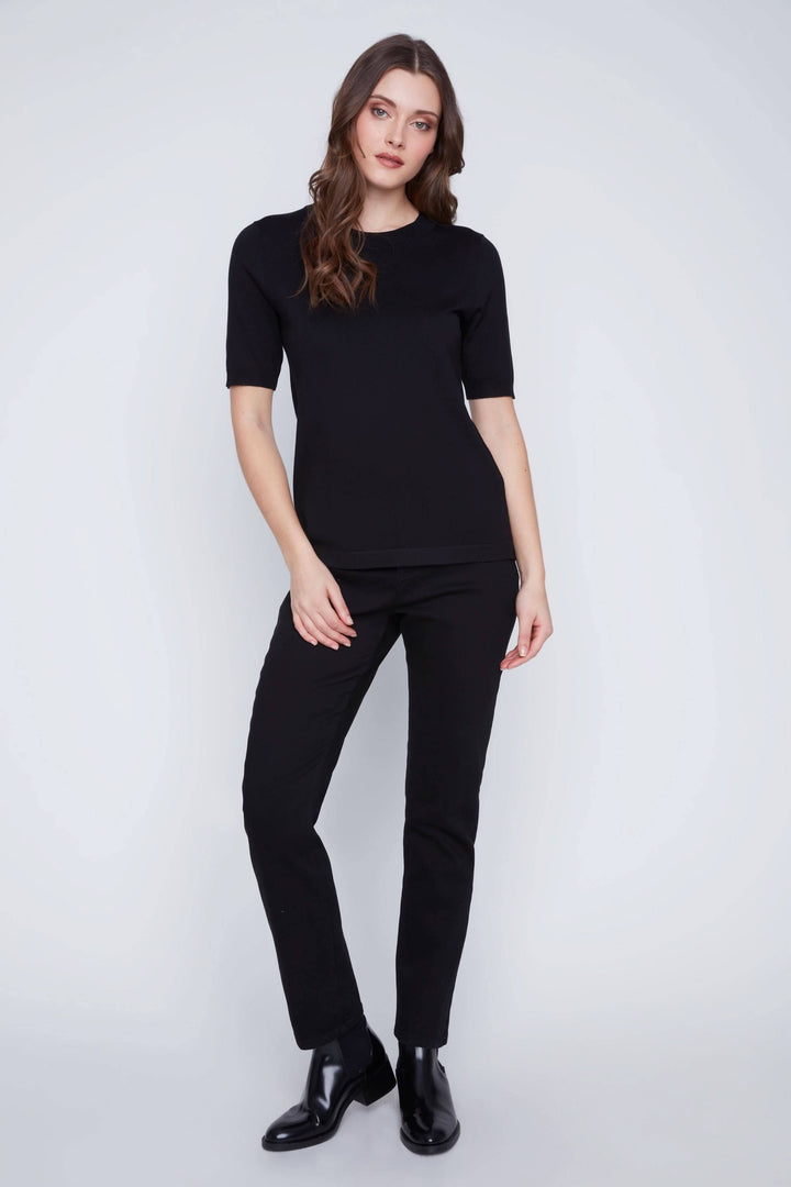 Femme portant un t-shirt classique noir à manches courtes avec un pantalon noir, style minimaliste élégant.