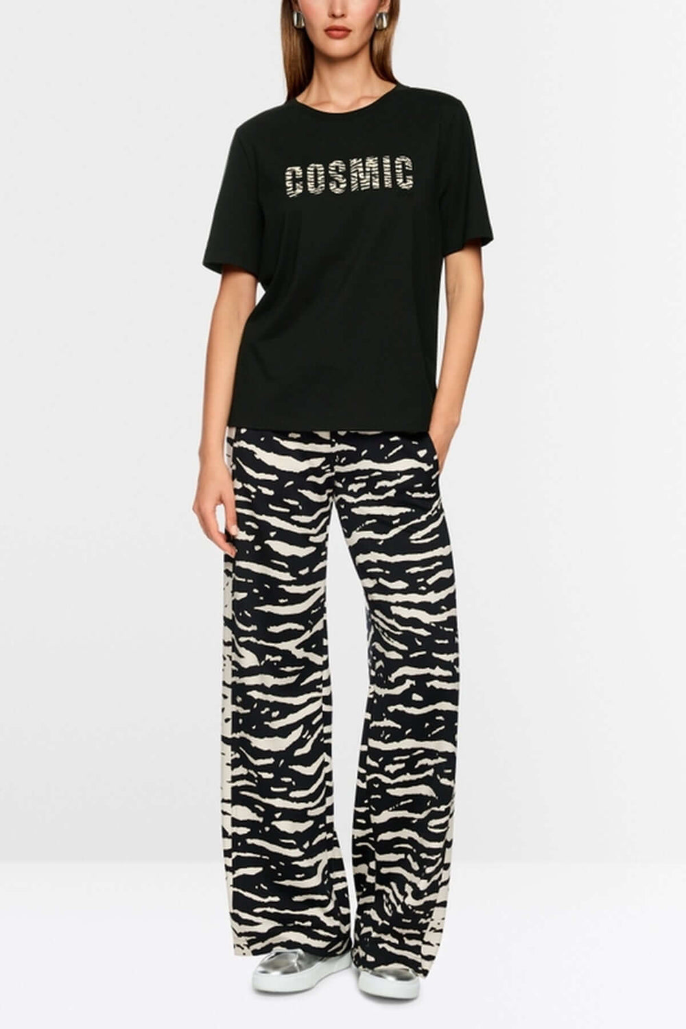 Femme portant un T-shirt classique col rond noir avec imprimé "Cosmic Love" et un pantalon imprimé animalier.