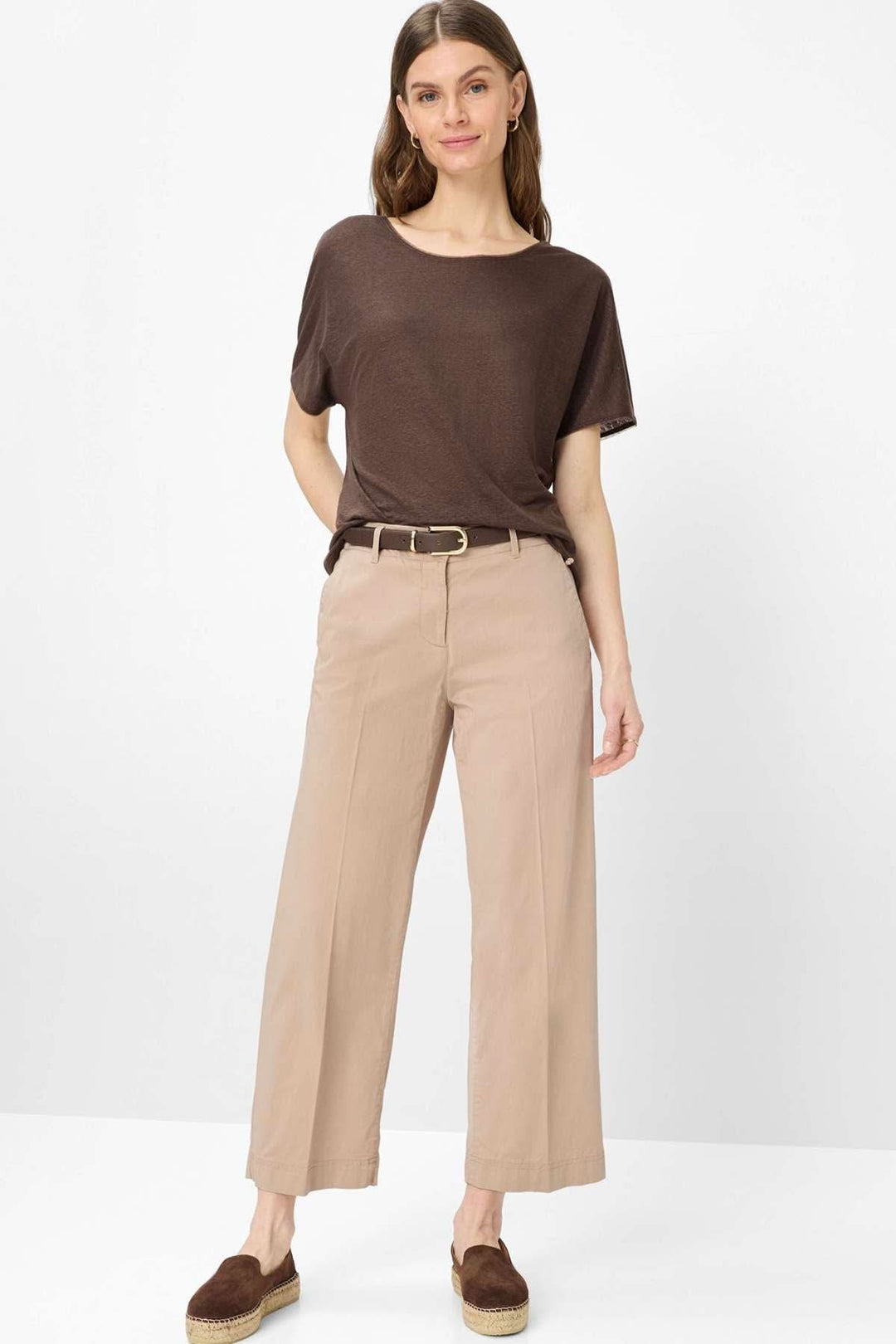 Femme portant un T-shirt col bateau Caelen marron avec un pantalon beige, tenue décontractée et élégante.