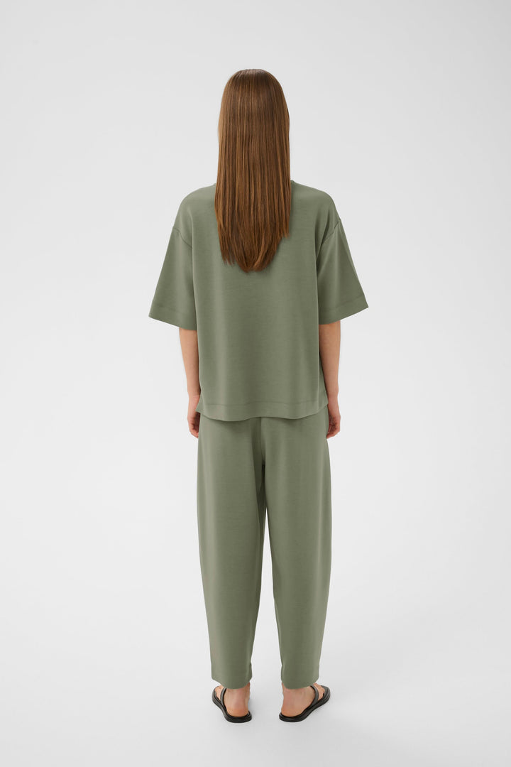 Vue arrière d'une femme portant un T-shirt Pannie ample et confortable, matière fluide, assorti à un ensemble coordonné, couleur vert olive.