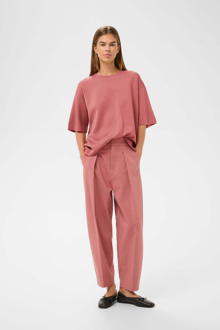 Femme portant le T-shirt Pannie à coupe ample en rose, avec pantalon coordonné, idéal pour un style décontracté et soigné.