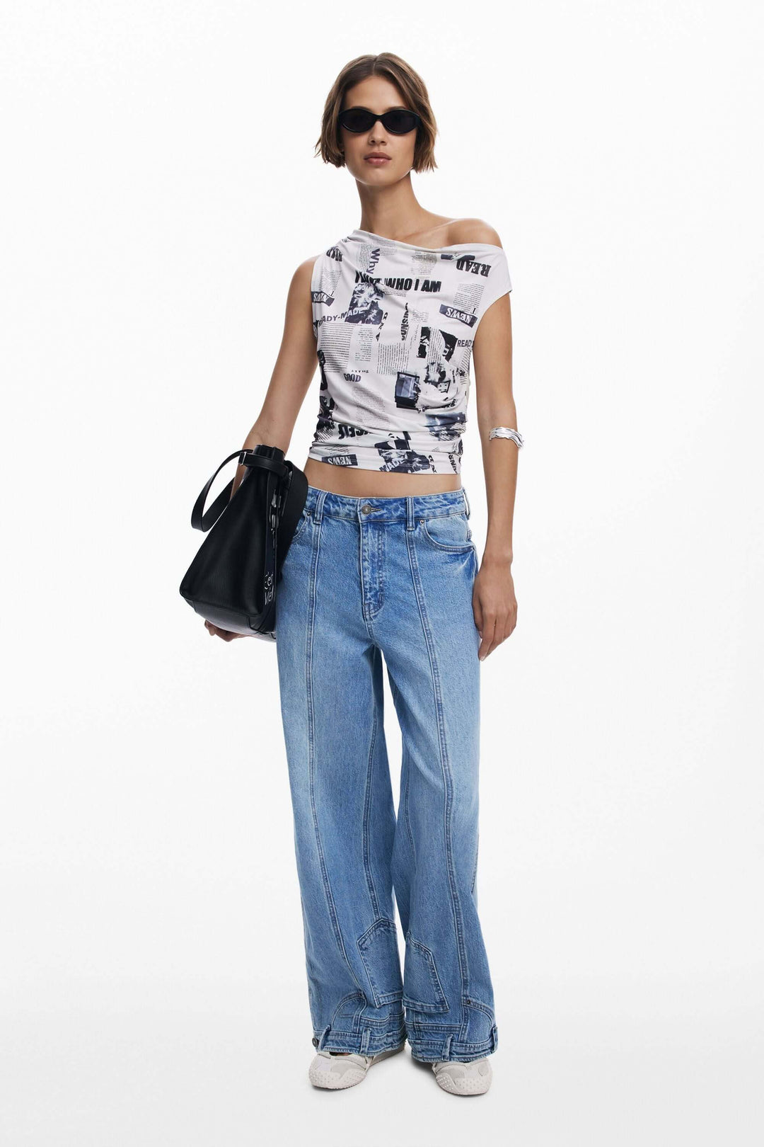 Femme portant un t-shirt drapé asymétrique avec imprimé typographique et un jean large, style moderne et urbain.