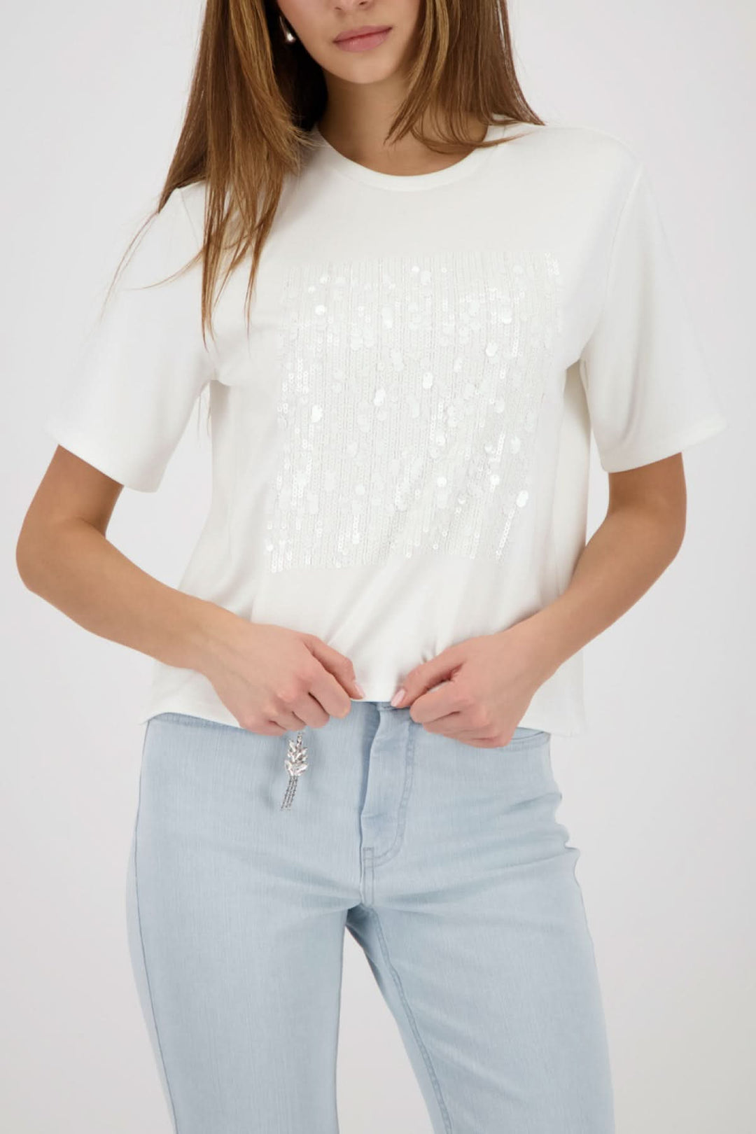 Femme portant un T-shirt à empiècement pailleté avec jean clair, style moderne et sophistiqué.