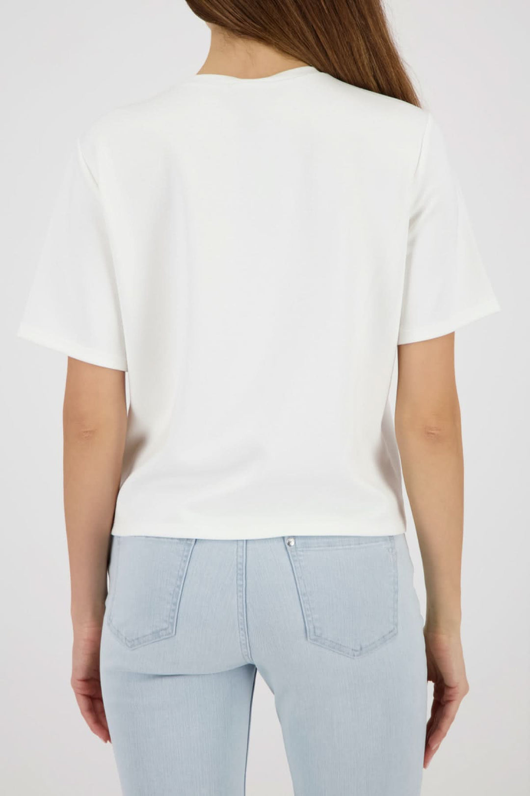 Vue arrière du T-shirt à empiècement pailleté blanc porté avec un jean clair, montrant la coupe droite et les manches courtes.