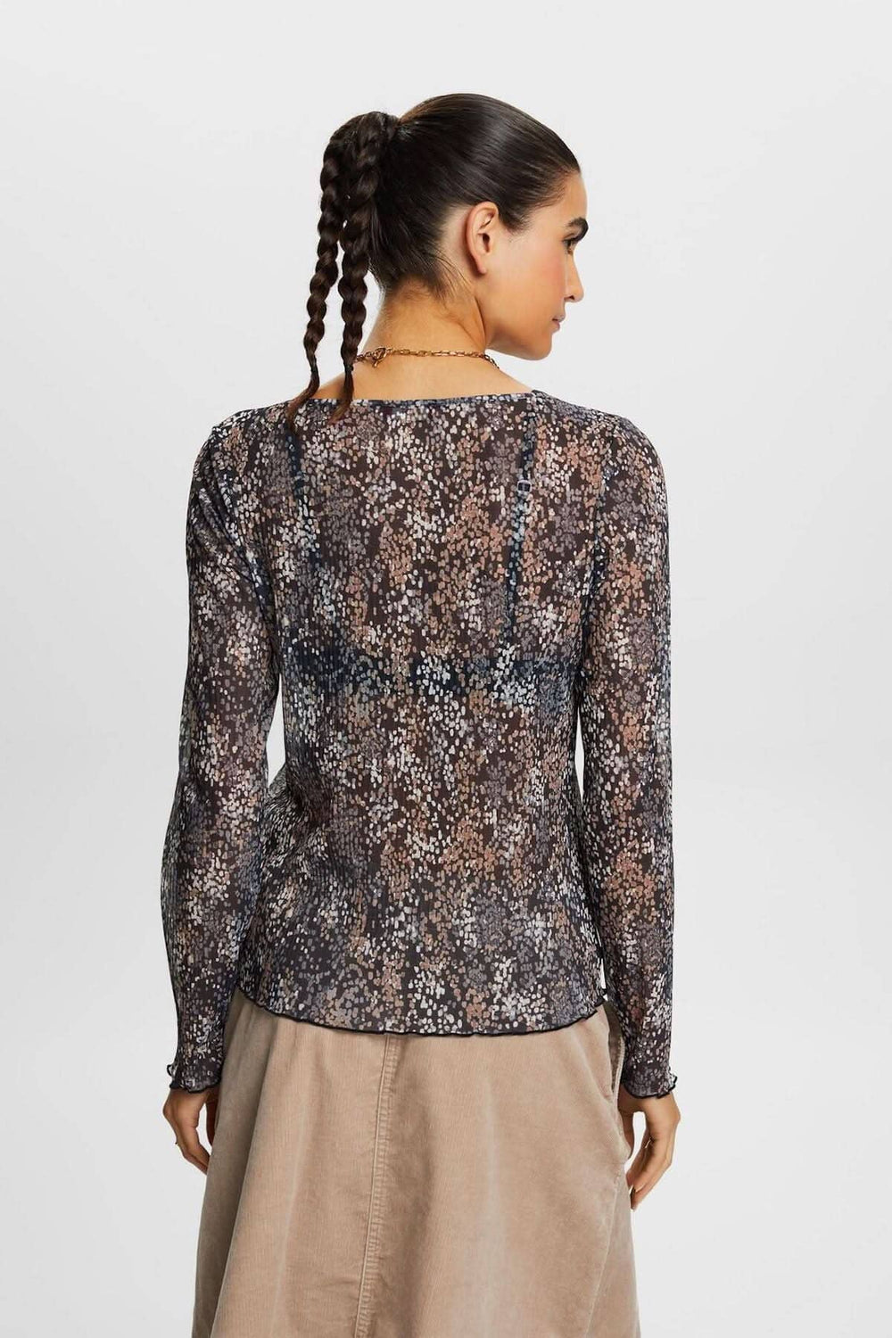 Vue arrière d'un t-shirt en mesh plissé à motif floral, élégant et semi-transparent, porté avec jupe.