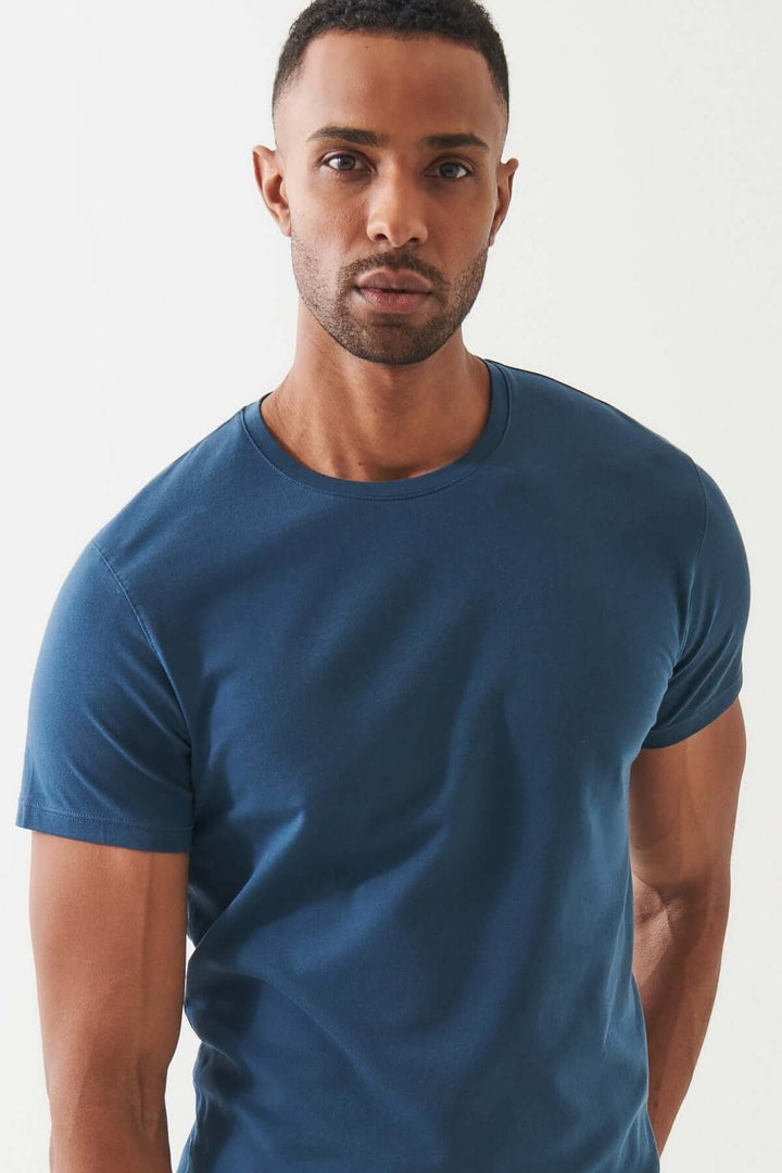 Homme portant un T-shirt bleu en coton Pima, symbole de luxe et confort intemporel.