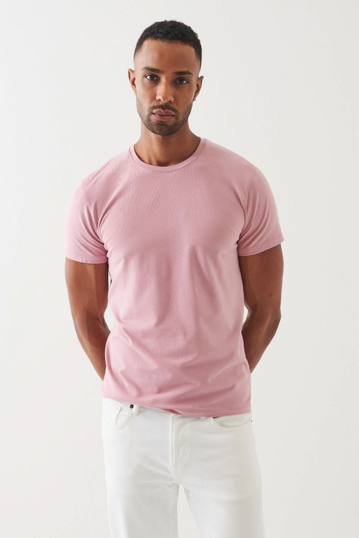 Homme portant un T-shirt en pima coton rose, affichant élégance et confort, avec un style décontracté.