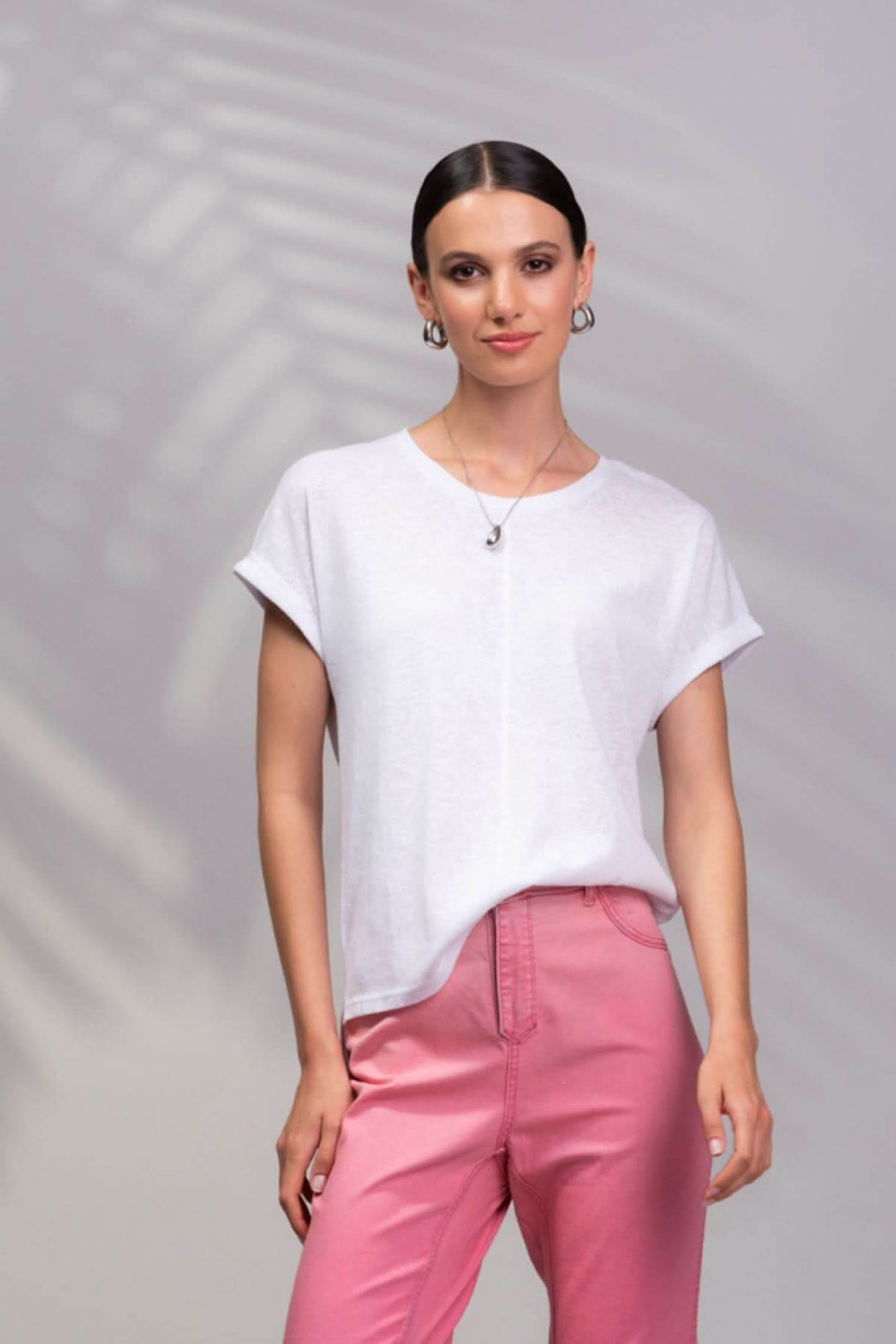 T-shirt encolure ronde blanc porté par une femme avec un pantalon rose, style décontracté et moderne.