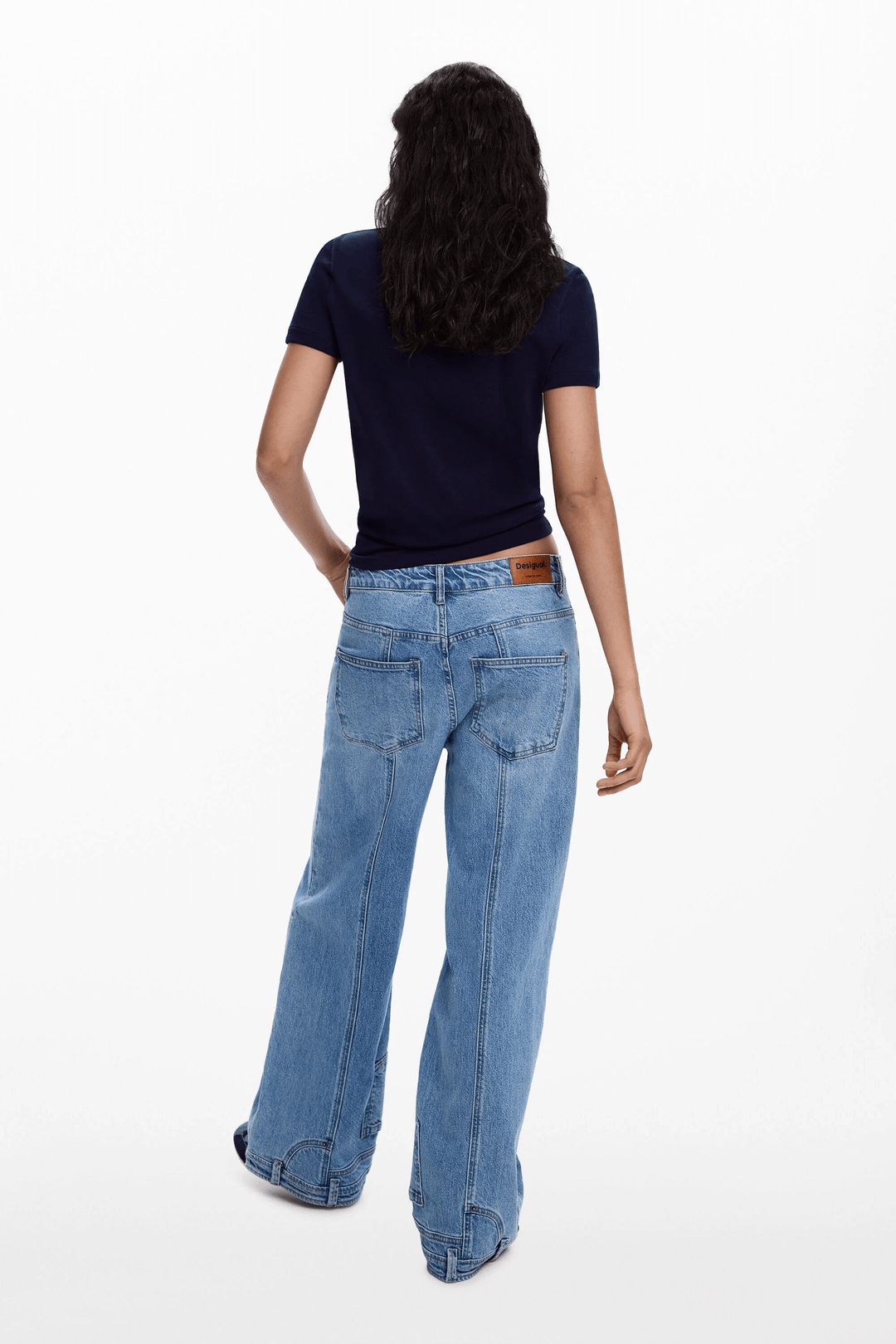 Person wearing blue jeans and a black T-shirt, viewed from the back