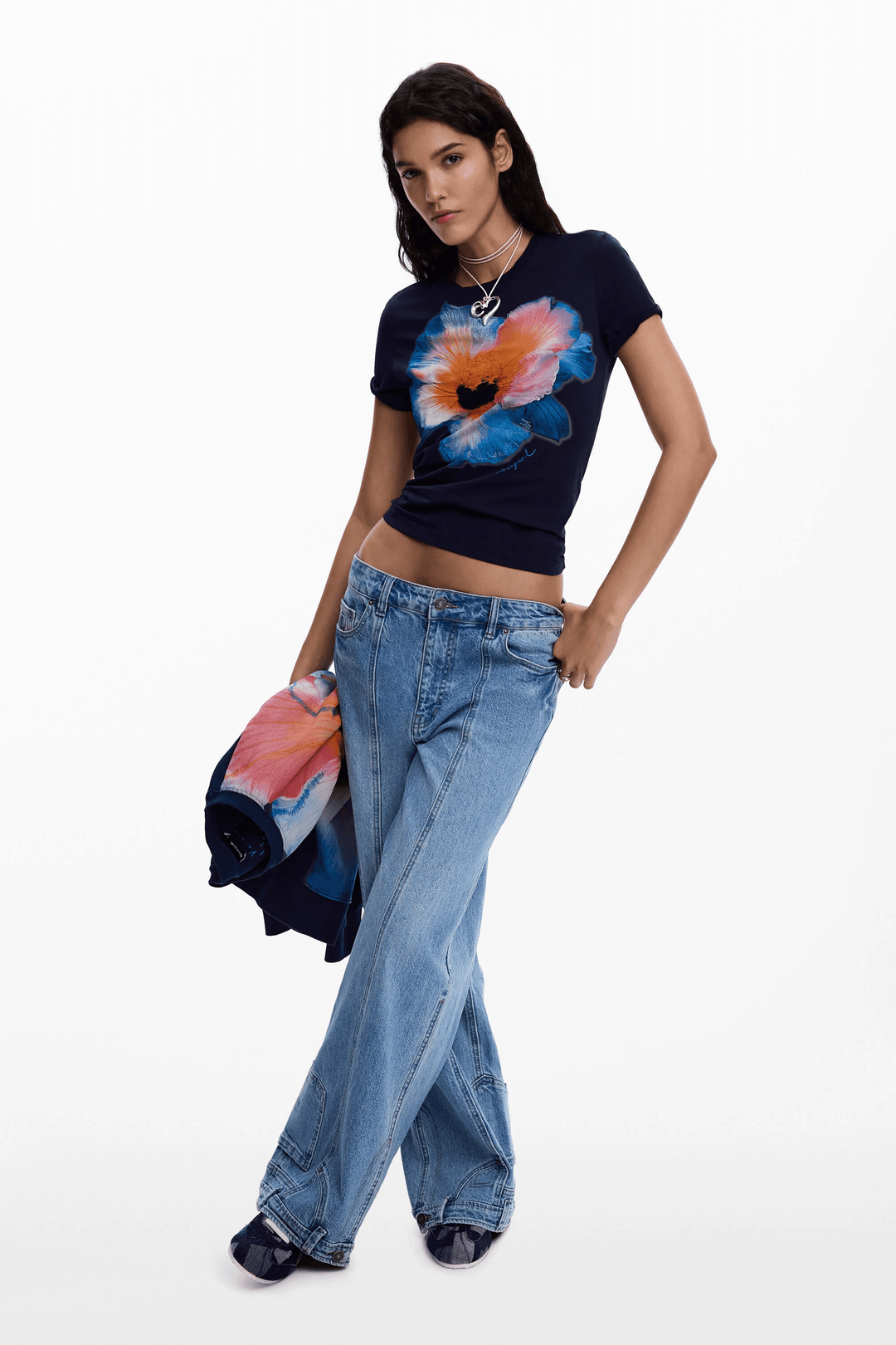 Femme portant un T-shirt grande fleur avec motif floral central, coupe ajustée et jeans décontractés.