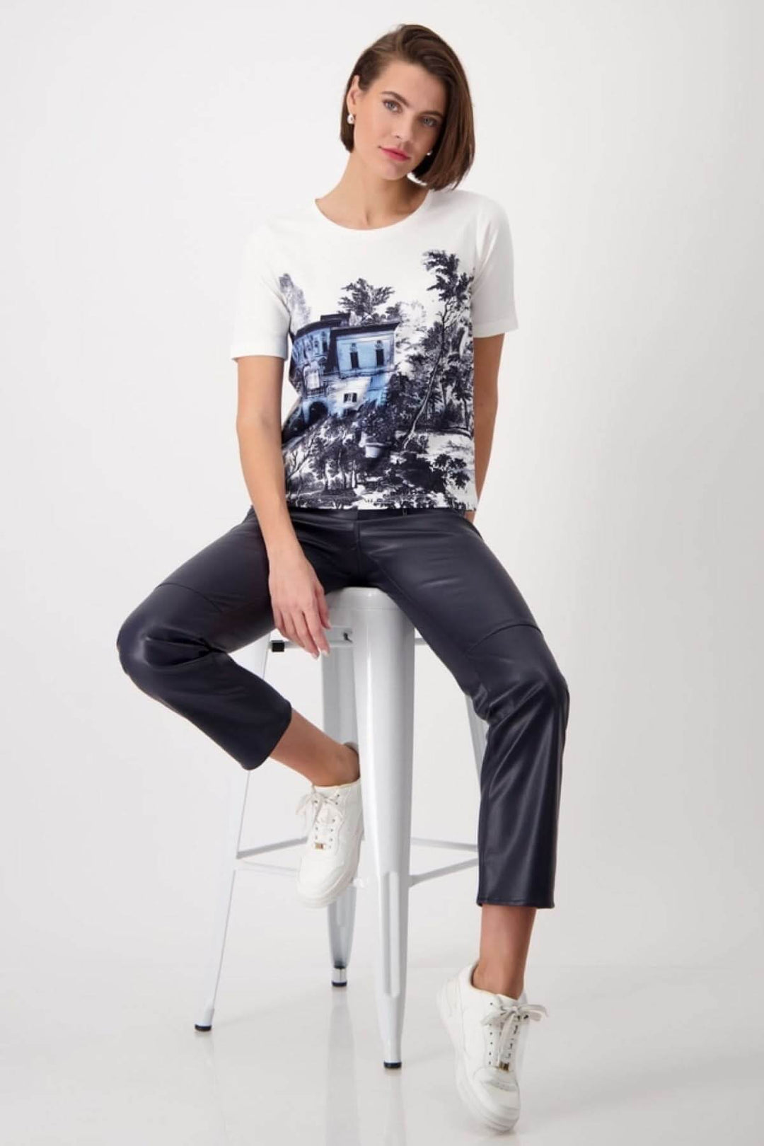 T-shirt imprimé «Jardin Anglais» porté par un mannequin avec un pantalon noir et des baskets blanches, look décontracté.