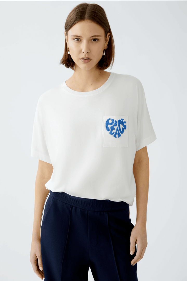 T-shirt blanc avec broderie "Peace" sur la poche, coupe ample et style décontracté.