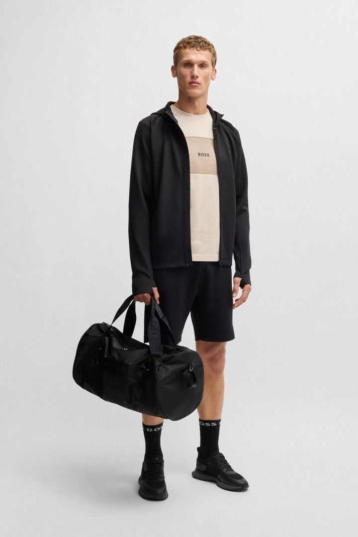 Homme portant un t-shirt BOSS, veste noire et short, avec un sac de sport noir.