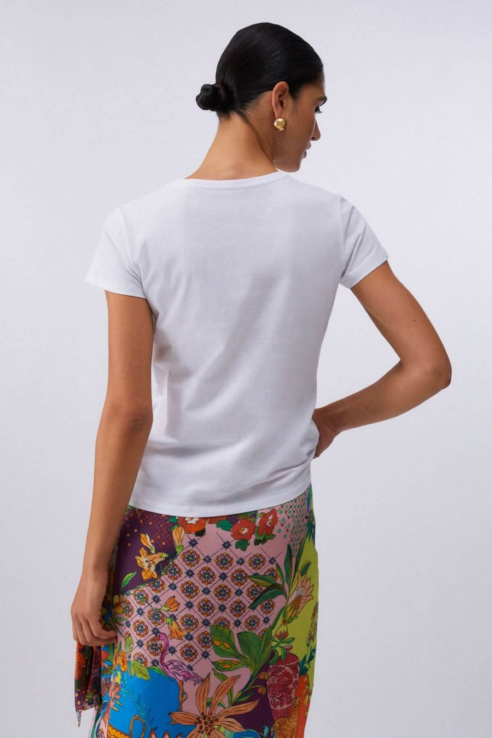 Vue arrière de la femme portant le T-shirt à manches courtes avec imprimé graphique, jupe colorée.