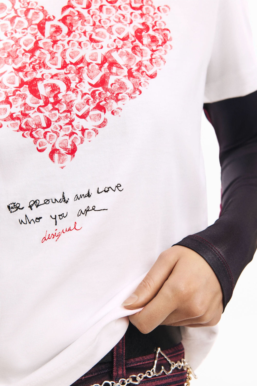 T-shirt à manches courtes coeur avec imprimé graphique de lettres formant un cœur et message inspirant, porté par une personne.