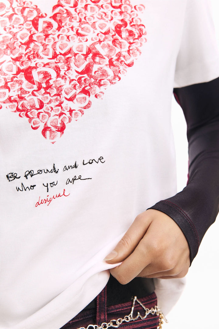 T-shirt à manches courtes coeur avec imprimé graphique de lettres formant un cœur et message inspirant, porté par une personne.