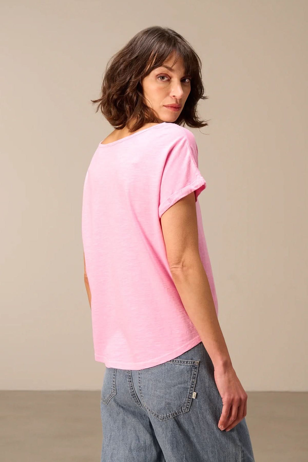 Femme portant un T-shirt à manches courtes coupe décontractée, couleur rose clair, vue de dos.