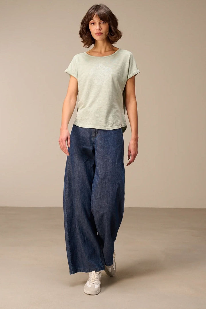 Femme portant un t-shirt à manches courtes coupe décontractée avec jean ample, silhouette moderne et confort naturel.