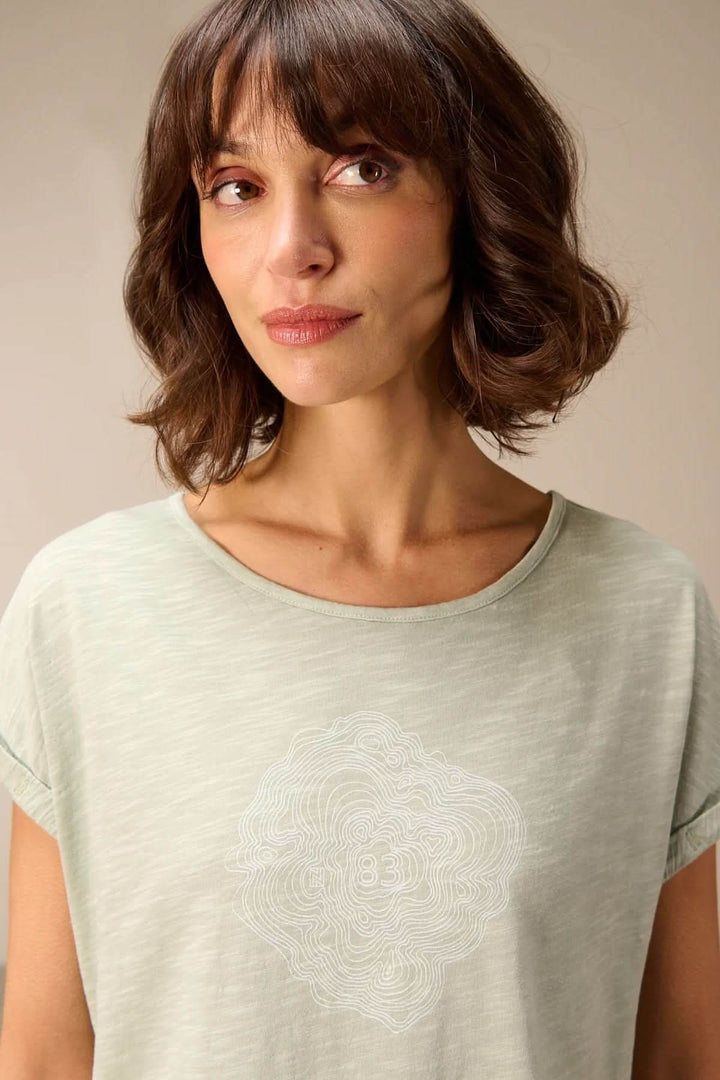 Femme portant un T-shirt à manches courtes coupe décontractée, en tissu léger et respirant avec un motif subtil.