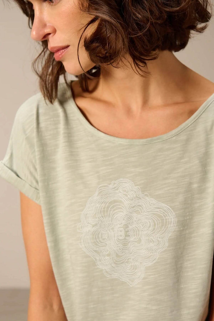 Femme portant un t-shirt à manches courtes coupe décontractée, en tissu léger avec design graphique, idéal pour un style quotidien.