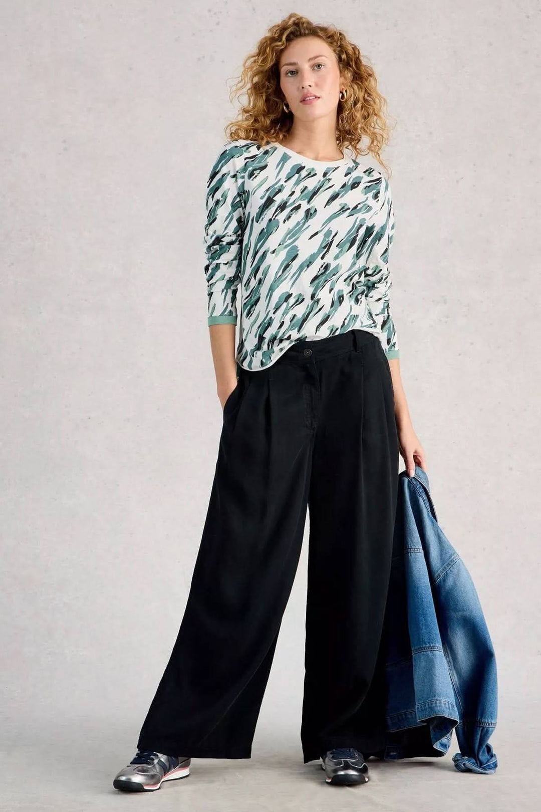 Femme portant le T-shirt à manches longues Clara au design simple et confortable, idéal pour le quotidien, avec un pantalon noir et une veste en jean.