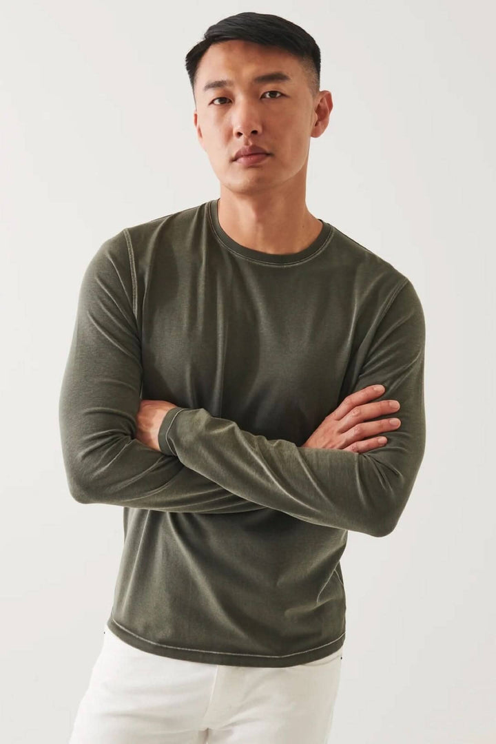 T-shirt à manches longues en coton pima, couleur olive, porté par un homme avec un style décontracté.
