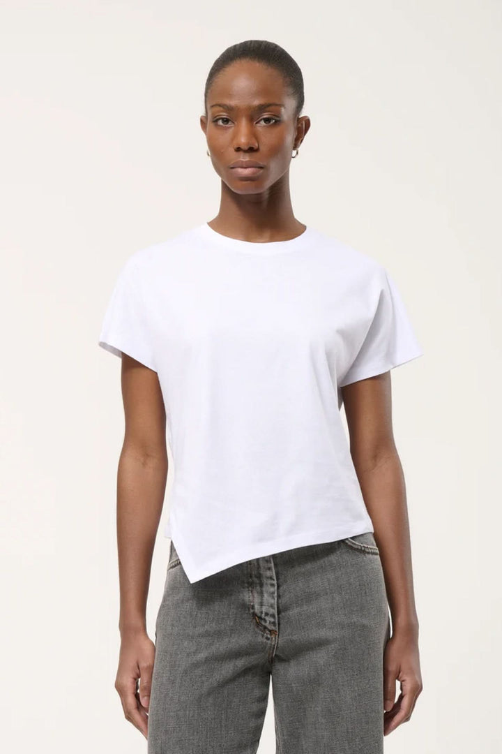 Femme portant un T-shirt à ourlet asymétrique blanc avec un jean, design moderne et élégant pour un style décontracté.