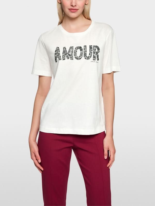 T-shirt à paillettes blanc avec lettrage "Amour", col rond et manches courtes en coton, porté par un mannequin.